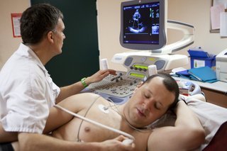Mężczyzna po echokardiogramie z czujnikami przymocowanymi do jego klatki piersiowej i obrazem na monitorze
